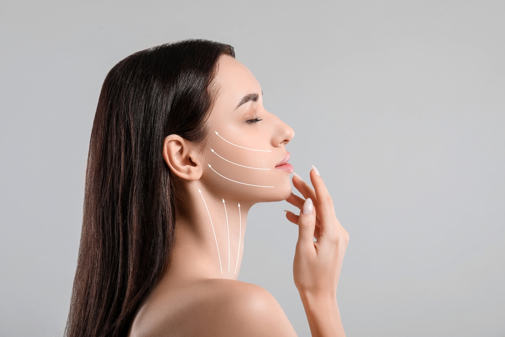 Female profile with white upward arrows on cheek and neck, hand gently touching chin