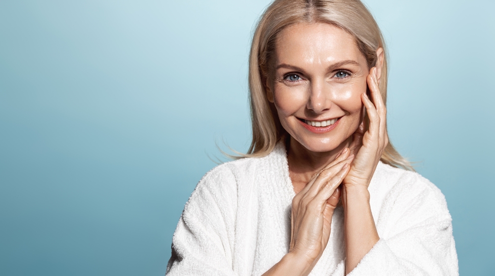 Smiling midlife woman in a robe with fresh, glowing skin, representing the Guinot Age Summum facial at our Glasgow beauty salon.